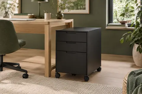 Caisson de bureau noir mat en acier à trois tiroirs, installé sur roulettes près d’un bureau en bois clair.