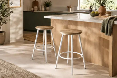 Deux tabourets de bar à assise ronde effet chêne et structure en acier blanc mat près d’un îlot