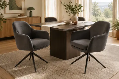 Deux chaises pivotantes en velours gris foncé avec accoudoirs et pieds en métal autour d’une table en bois
